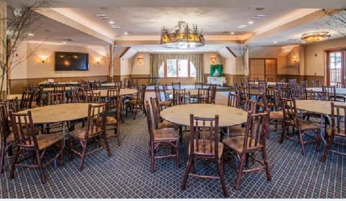 a dining room with tables and chairs and a chandelier at Woodstock Inn, Station and Brewery in North Woodstock