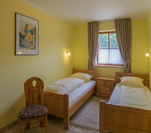 une chambre avec deux lits et une chaise et une fenêtre dans l'établissement Hofbauerngut Sprödhuber, à Passau