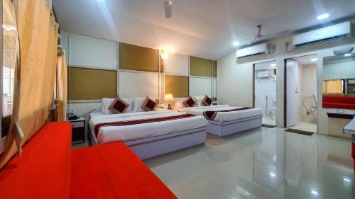 a hotel room with two beds and a red couch at Rainforest Resort and Spa, Igatpuri -Nature's Luxury Awaits in Igatpuri