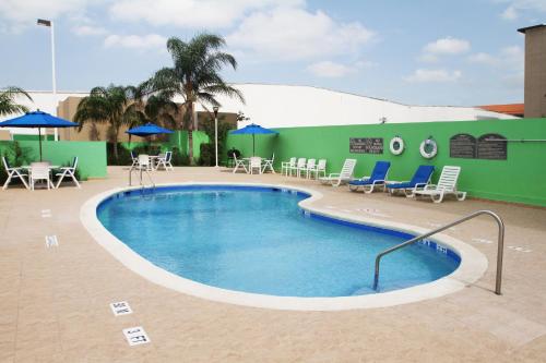 uma piscina num hotel com cadeiras e guarda-sóis em Holiday Inn Express & Suites Monterrey Aeropuerto, an IHG Hotel em Monterrey