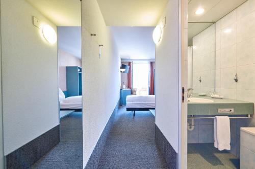 ein Hotelzimmer mit einem Bad mit einem Bett und einem Waschbecken in der Unterkunft Hotel City am Bahnhof in Bern
