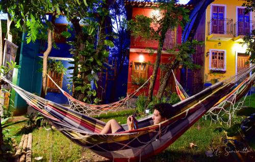 a woman sitting in a hammock in front of a house at Chalés Natora in Lençóis