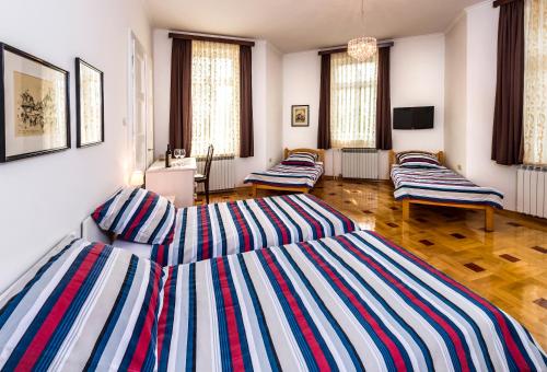a living room with three striped beds in it at Vila Regina rooms in Karlovac