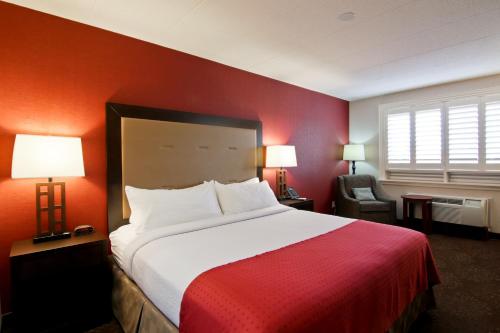 Habitación de hotel con cama y pared roja en Holiday Inn Hotel & Suites St.Catharines-Niagara, an IHG Hotel, en St. Catharines