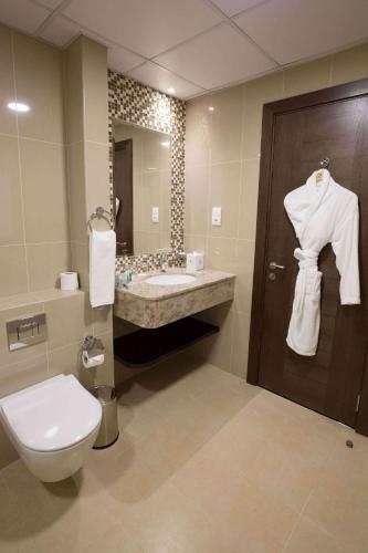 a bathroom with a toilet and a sink and a mirror at Gulf Executive Hotel & Residence Juffair in Manama
