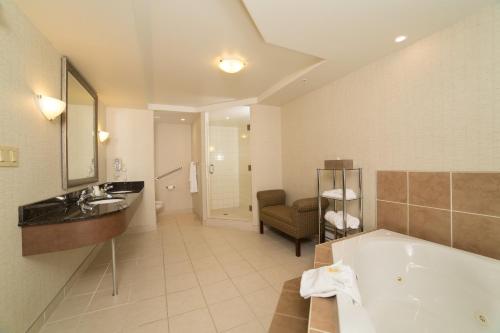 a bathroom with a tub and a sink at Holiday Inn & Suites Lloydminster, an IHG Hotel in Lloydminster