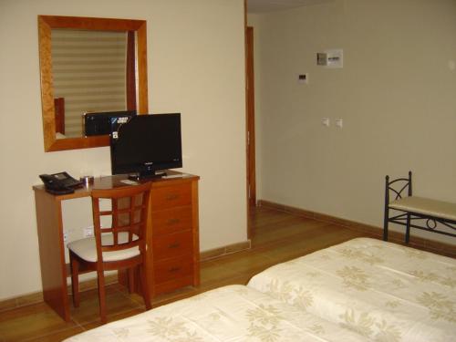 a bedroom with a desk with a television and a bed at HOTEL PLAZA in Talarrubias