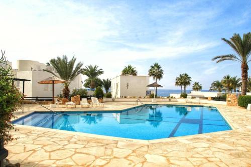 einen Pool in einem Resort mit Palmen und dem Meer in der Unterkunft Sea front Villa Kristina in Klorakas