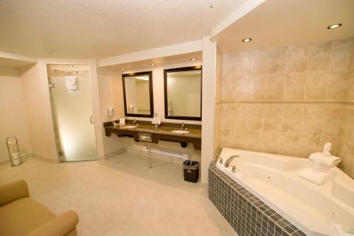 a bathroom with a tub and two sinks and a bath tub at Holiday Inn Hotel & Suites-West Edmonton by IHG in Edmonton
