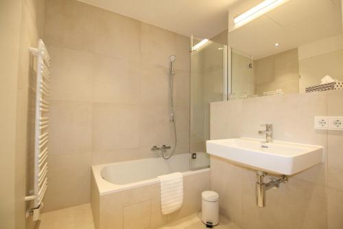 a white bathroom with a sink and a bath tub at Your Living Vienna CBD in Vienna