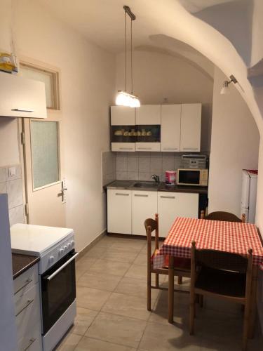 a kitchen with white cabinets and a table with a tablecloth at Apartman Bécsi utca in Sopron
