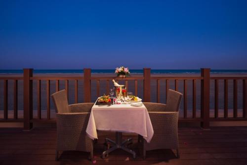a table with a plate of food and flowers on a balcony at Masira Island Resort in Ḩilf