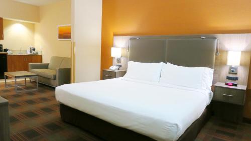 a hotel room with a large bed and a chair at HOLIDAY INN EXPRESS & SUITES ELK GROVE CENTRAL - HWY 99 by IHG in Elk Grove