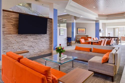 a lobby with couches and a tv on a brick wall at HOLIDAY INN EXPRESS & SUITES ELK GROVE CENTRAL - HWY 99 by IHG in Elk Grove