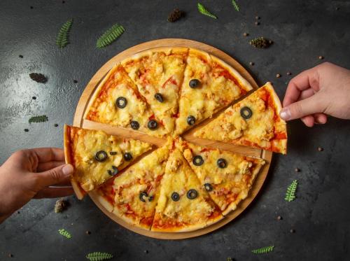 a person holding a slice of pizza on a table at Macara Sheki City Hotel in Sheki
