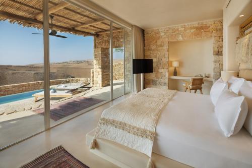 a bedroom with a large white bed and a large window at Six Senses Shaharut in Shaharut