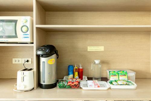 a coffee maker sitting on a shelf next to a microwave at Riski Residence Bangkok-noi - Wasit Apartment in Bangkok