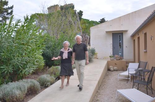 un uomo e una donna più vecchi che camminano in un giardino di L' Oustau Blanc B&B a Fontvieille