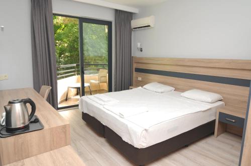 a bedroom with a bed and a table and a balcony at Club Palm Garden Keskin Hotel in Marmaris