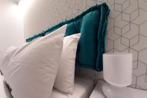 Athenian Montaza Hotel في أثينا: سرير مع وسائد بيضاء وطاولة خضراء للرأس