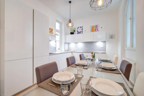 a white dining room with a table and chairs at Bishop Apartments in Brno
