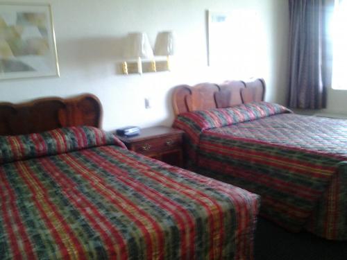 a hotel room with two beds and a table at Budget Inn in Tulare