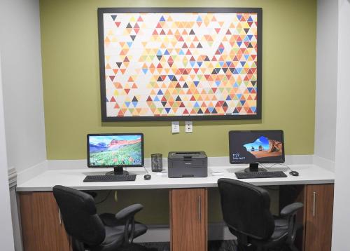 two computers sitting on a desk with chairs at Holiday Inn Express & Suites - Valdosta by IHG in Valdosta
