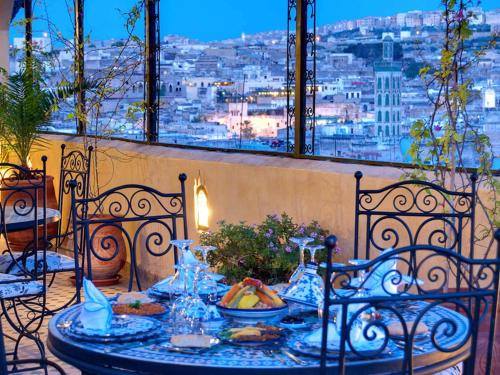 a table with food on a balcony with a view of a city at Riad Rcif & Spa Originale in Fès