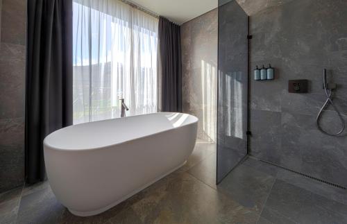 a white bath tub in a bathroom with a window at Hotel Geysir in Geysir