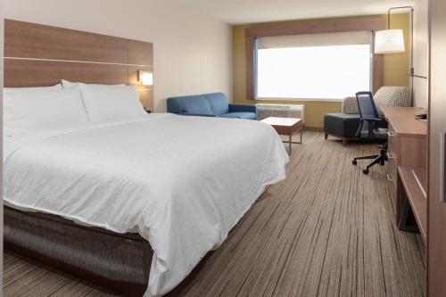 Cette chambre comprend un grand lit et une chaise. dans l'établissement Holiday Inn Express & Suites - Gilbert - East Mesa, an IHG Hotel, à Gilbert