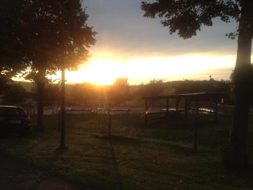 a sunset in a field with a park with benches at Penthouse Mosel Hunter in Gornhausen