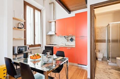 eine Küche mit orangefarbenen Schränken sowie einem Tisch und Stühlen in der Unterkunft Rifredi & Dalmazia Modern Loft in Florenz