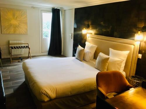 a bedroom with a large bed and a chair at Hotel Acadie Orly Morangis in Morangis