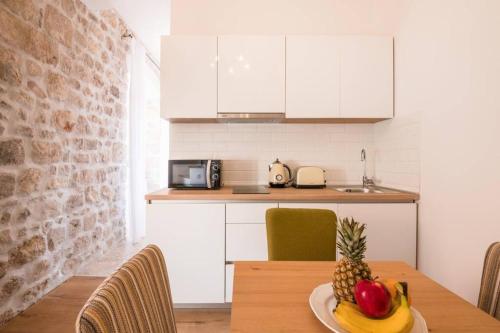 a kitchen with a table with a plate of fruit on it at The Saint Blaise Old Town Swanky Heritage in Dubrovnik