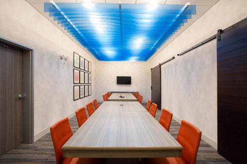 a conference room with a long table and orange chairs at Holiday Inn Express & Suites - Denver NE - Brighton by IHG in Brighton