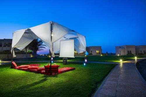 a white tent on a lawn at night at Masira Island Resort in Ḩilf