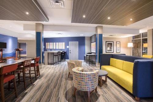 a lobby with a yellow couch and tables and chairs at Holiday Inn Express & Suites - Denver NE - Brighton by IHG in Brighton