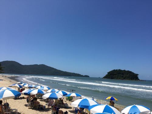 a beach with blue and white umbrellas and the ocean at Kaliman Pousada in Ubatuba