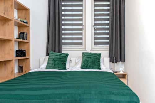 a bedroom with a green bed with two green pillows at 3D KOSCIUSZKI 19 Apartament in Kraków