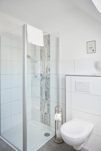 a white bathroom with a shower and a toilet at Liegeplatz Appartements in Fockbek