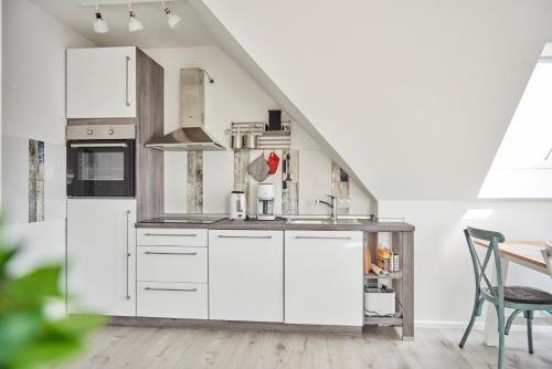 a kitchen with white cabinets and a staircase at Liegeplatz Appartements in Fockbek