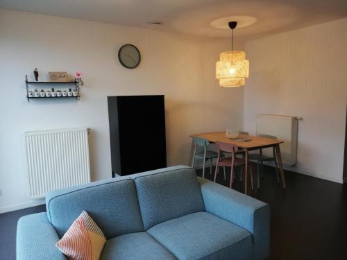 a living room with a blue couch and a table at Happiness De Haan in De Haan