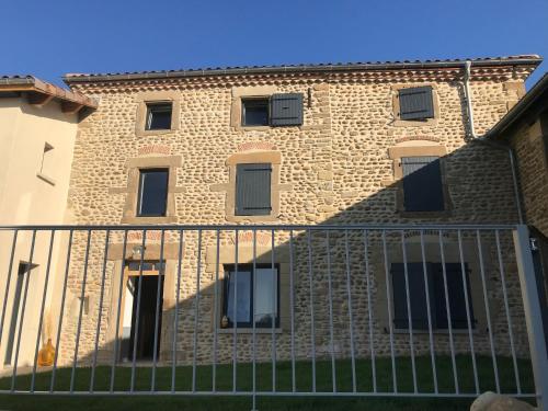 a brick building with a fence in front of it at La Maison de Paul & Margaux in Châteauneuf-de-Galaure