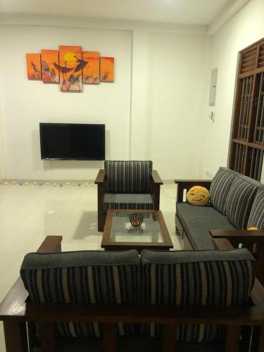 a living room with two couches and a tv at Lanka Villa Mirissa in Mirissa