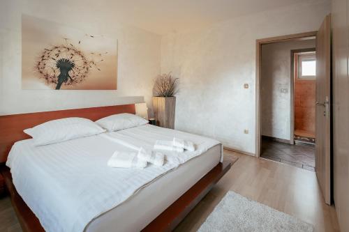 1 dormitorio con 1 cama grande con sábanas y almohadas blancas en Apartments in Villa Olimp, en Liubliana