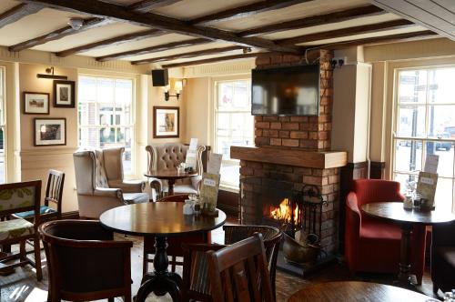 een restaurant met tafels en een open haard en stoelen bij Ye Olde Talbot Hotel by Greene King Inns in Worcester
