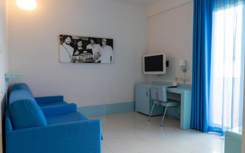 a room with a blue chair and a desk with a computer at Domina Zagarella Sicily in Santa Flavia