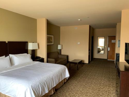 ein Hotelzimmer mit einem großen Bett und einem Sofa in der Unterkunft Holiday Inn Express & Suites Pecos, an IHG Hotel in Pecos
