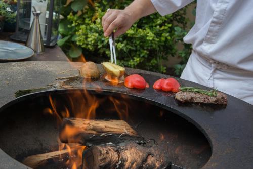 a person is cooking some food on a grill at Monastery Garden Prague in Prague