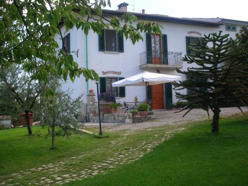 a white house with an umbrella in a yard at Casa Vacanze Bellavista in San Casciano in Val di Pesa